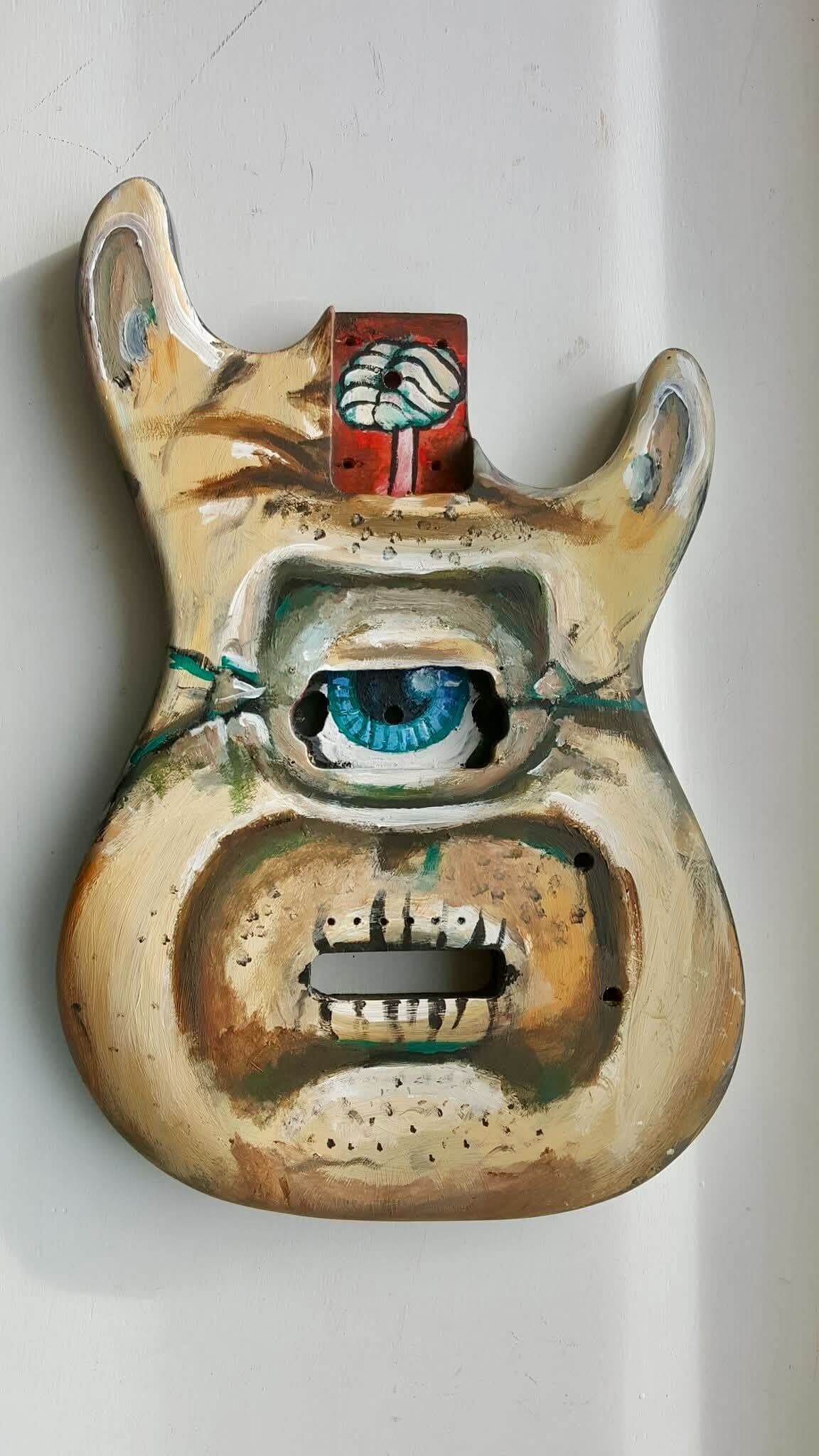 Custom painted electric guitar body with a blue eye and creature face design