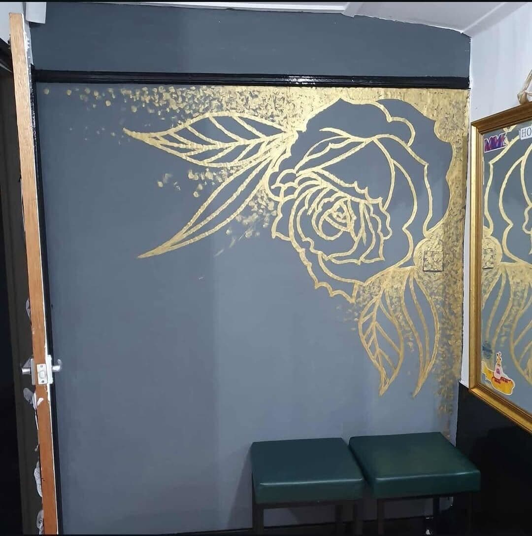 Gold rose and leaves mural on a dark grey wall